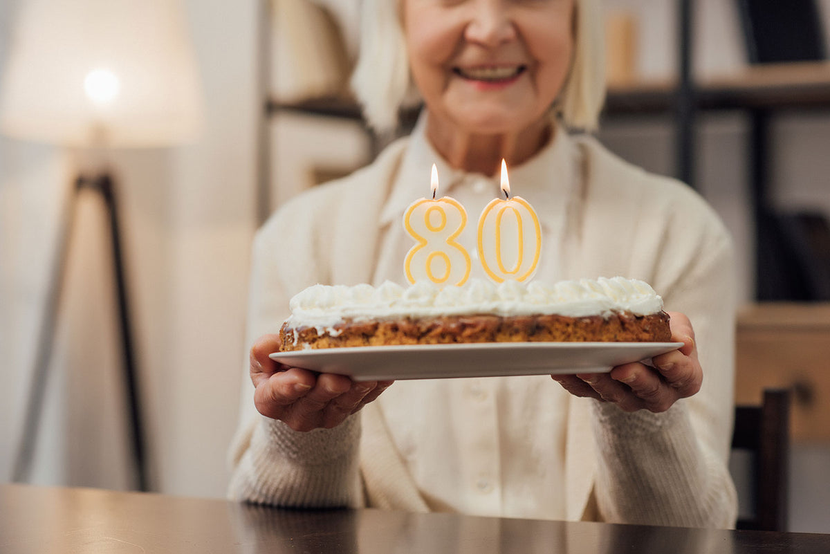 Ältere Dame feiert ihren 80. Geburtstag mit einem Geburtstagskuchen