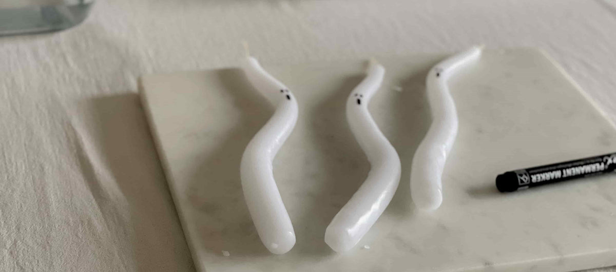 Gruselige Stabkerze, die als Geist für Halloween Deko gestaltet ist.