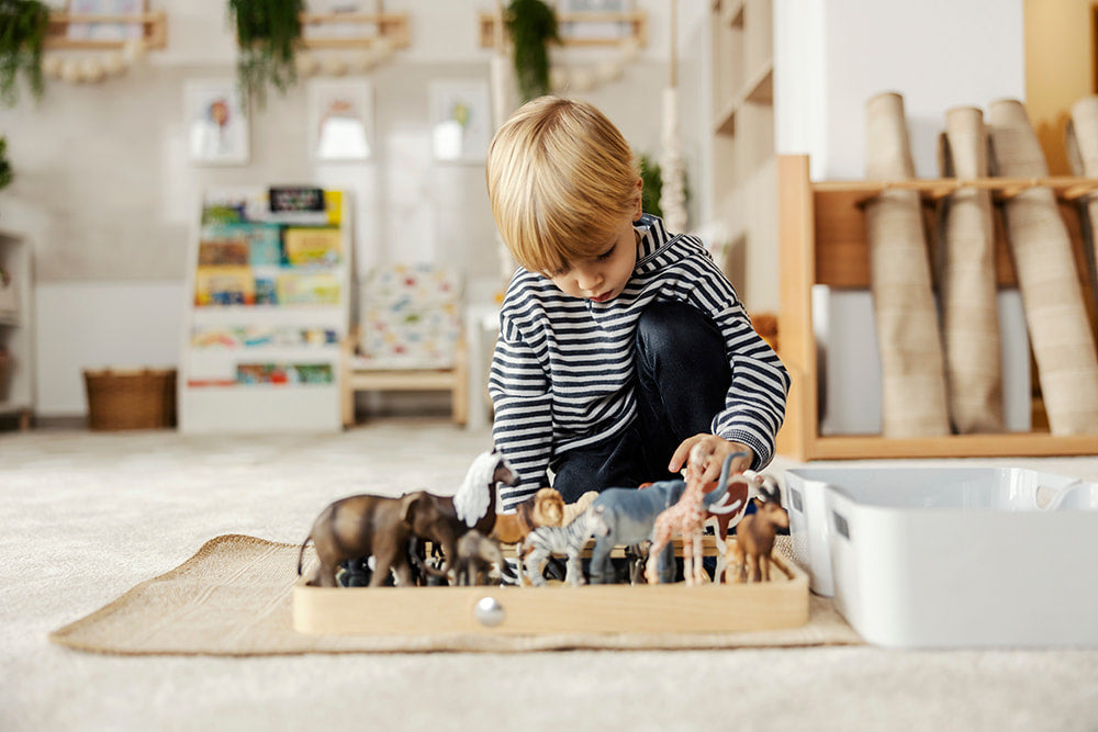 Kleiner Junge spielt mit Spielzeug im Kinderzimmer