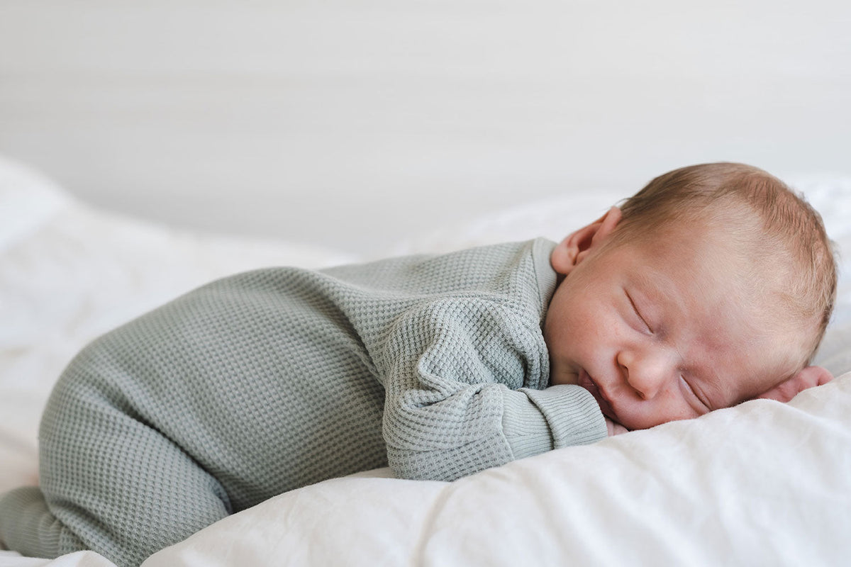 Schlafendes Baby in pastellfarbener, hellblauer Kleidung