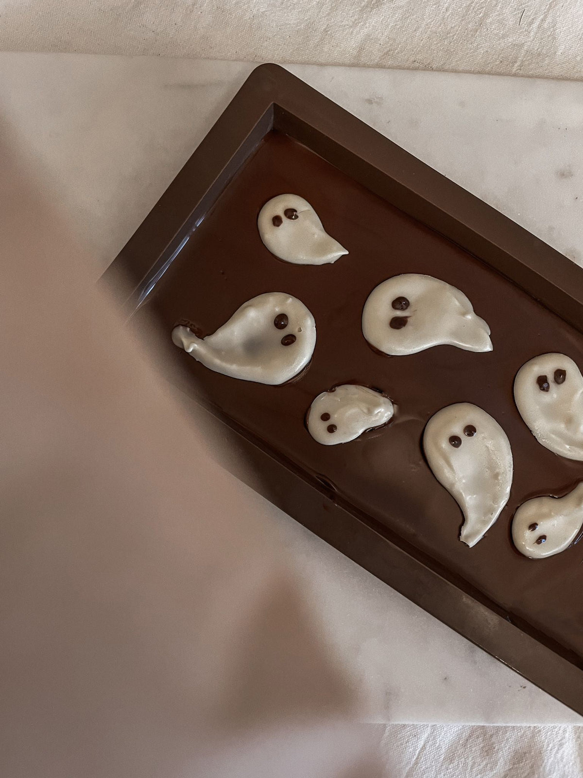 Fertige Halloween DIY Schokoladentafel mit weißen Geistern, stilvoll auf dem Tisch präsentiert – perfekte Herbstdekoration und Snack.