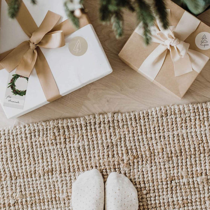 Stilvolle, nordisch verpackte Geschenke unter dem Weihnachtsbaum in natürlichen Farben mit Grünakzente