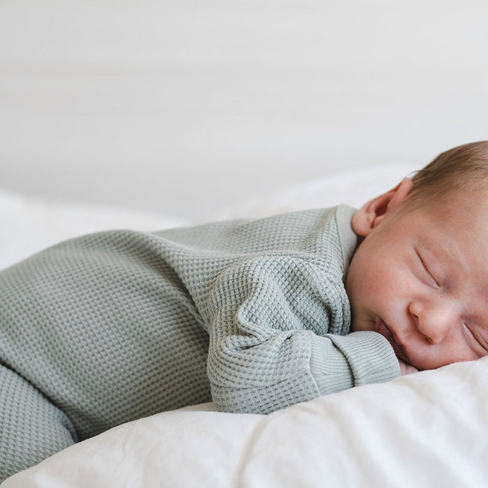 Schlafendes Baby in pastellfarbener, hellblauer Kleidung
