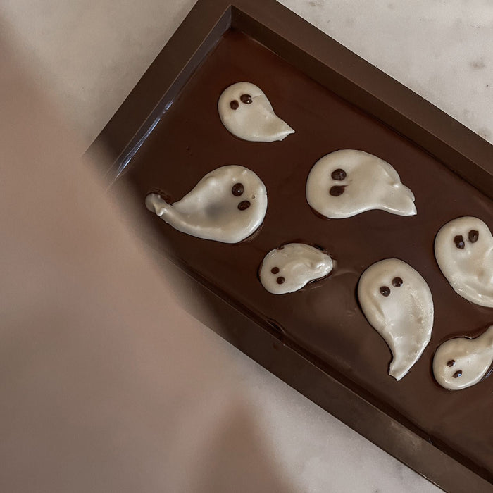 Fertige Halloween DIY Schokoladentafel mit weißen Geistern, stilvoll auf dem Tisch präsentiert – perfekte Herbstdekoration und Snack.