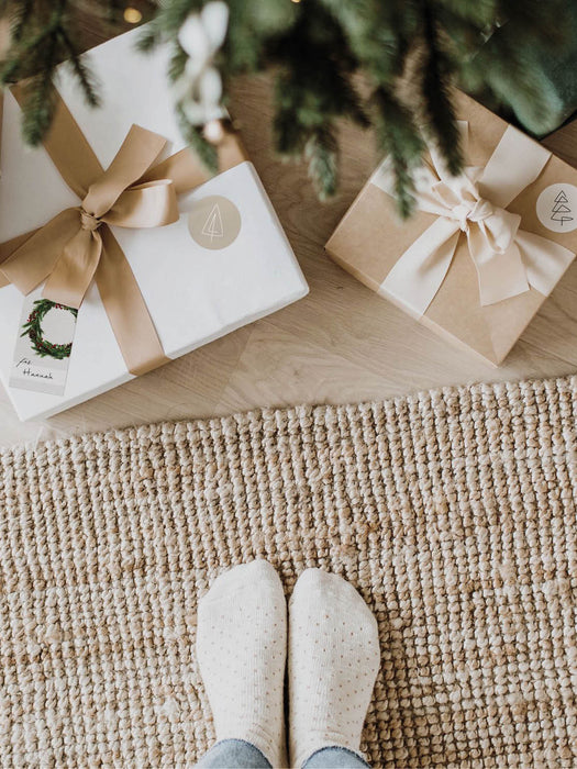 Stilvolle Geschenke mit Geschenkanhänger Weihnachtskranz unter dem Weihnachtsbaum mit grünfarbenen Akzenten